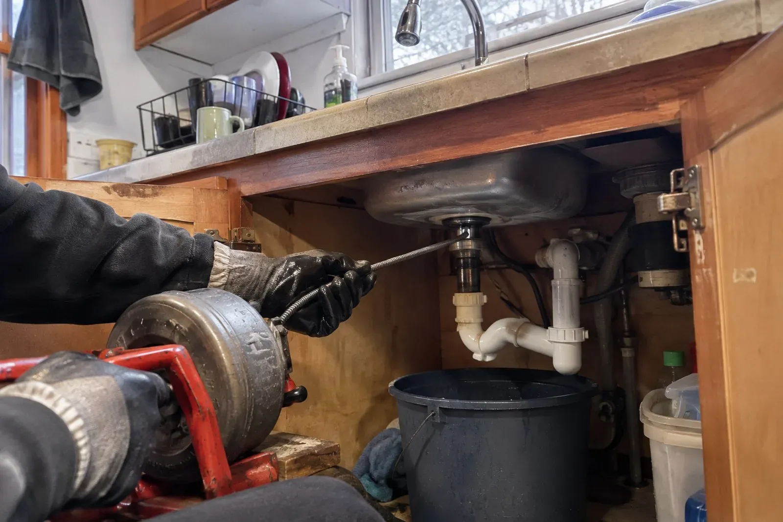 Plumber reaching under a sink to work on the drain trap in a Milwaukie home