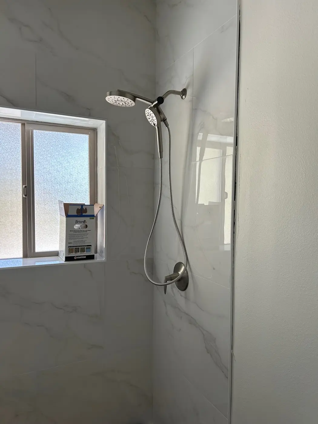 Marble-look tile shower with brushed nickel rainfall head and handheld wand by Wild Pine Plumbing in Portland, Oregon