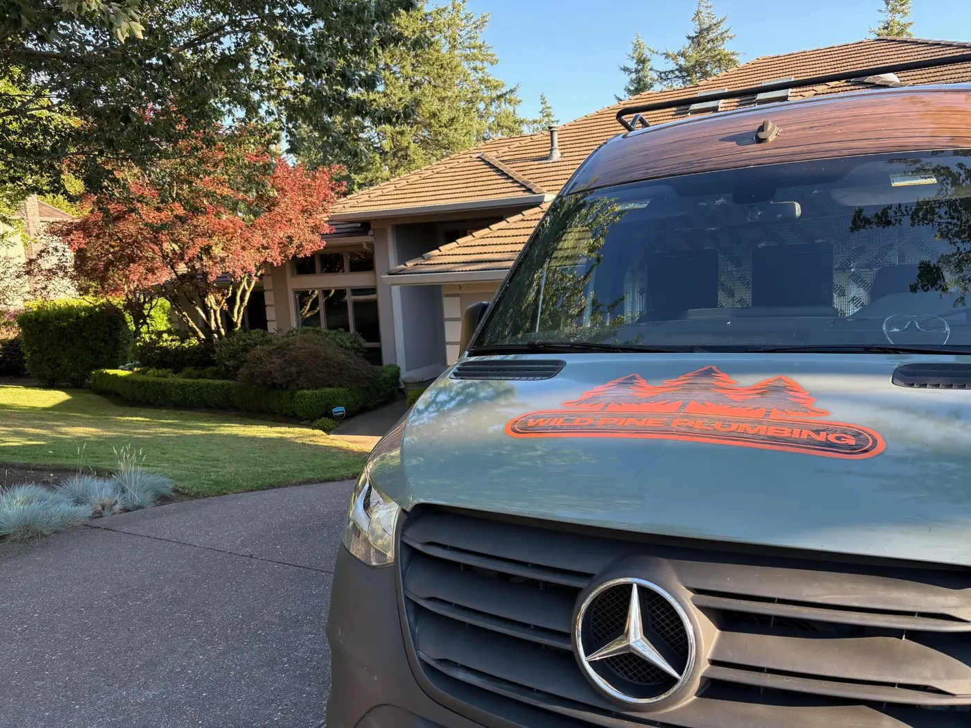 Wild Pine Plumbing Mercedes Sprinter service van parked at a Portland, Oregon home with Japanese maple landscaping