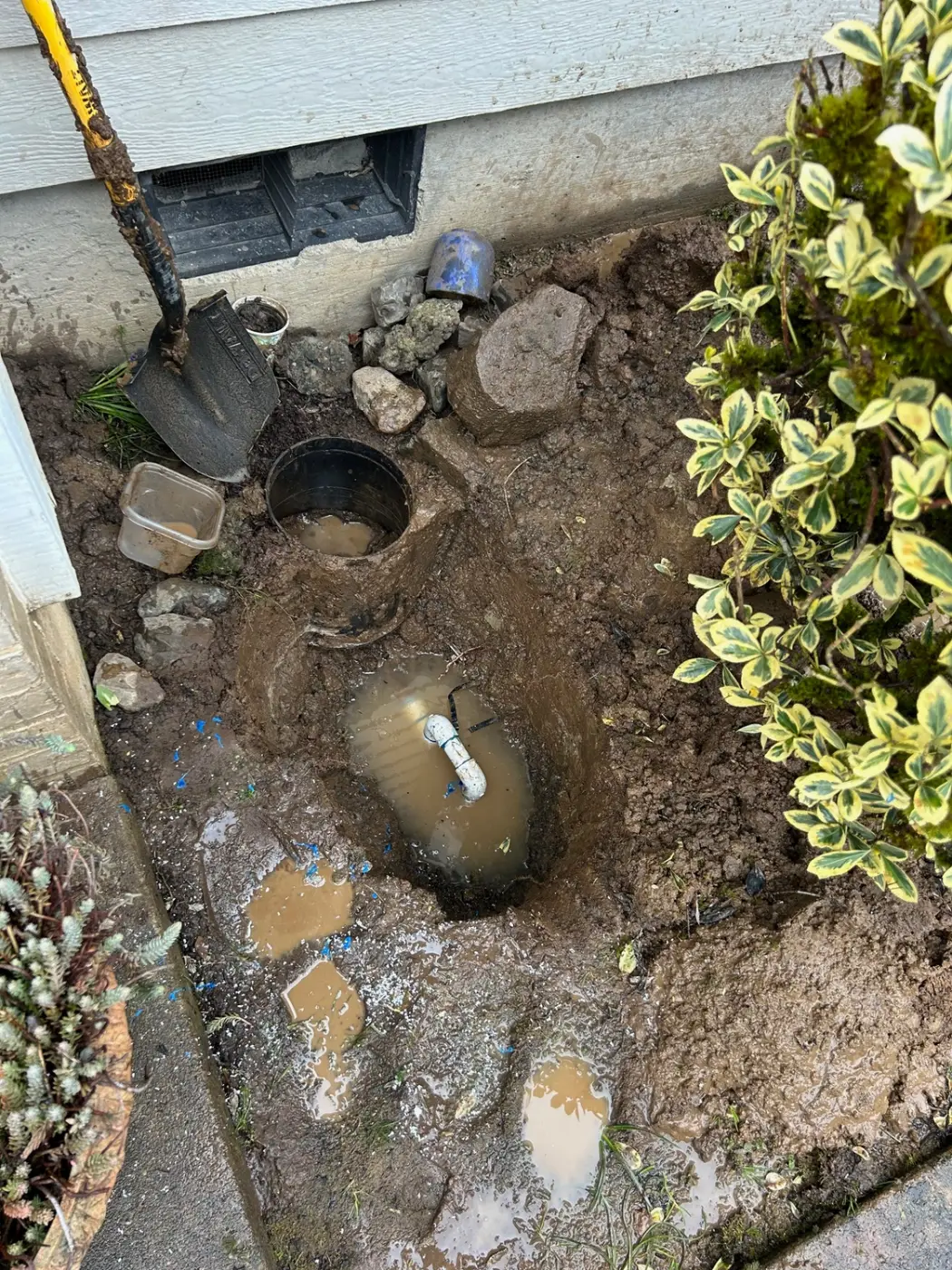 Water service line leak repair excavation next to a home foundation by Wild Pine Plumbing in Portland, Oregon