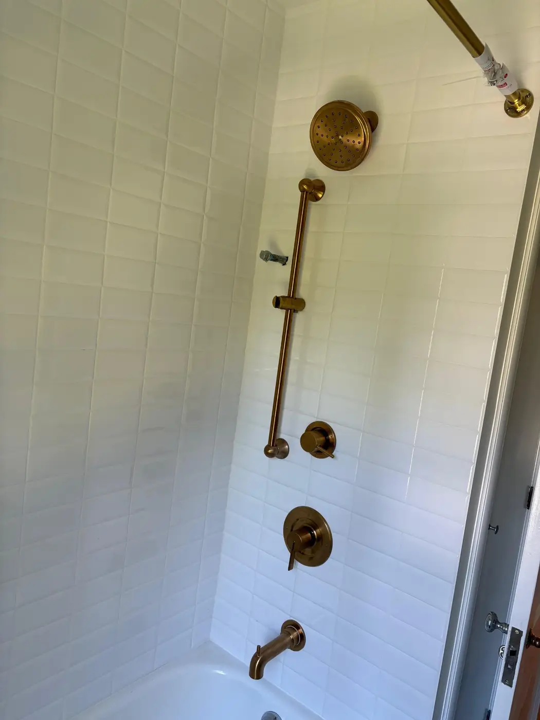 White picket tile tub-shower with antique brass rainfall head, slide bar, and tub spout by Wild Pine Plumbing in Portland, OR