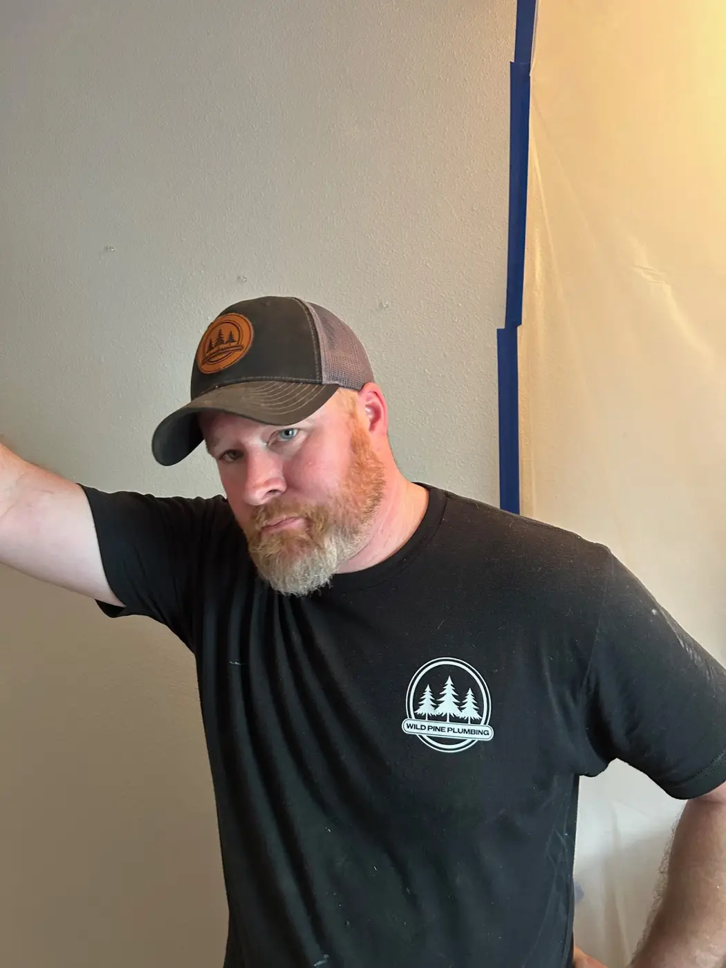 Wild Pine Plumbing owner in branded shirt and cap on a remodel job site in Portland, Oregon