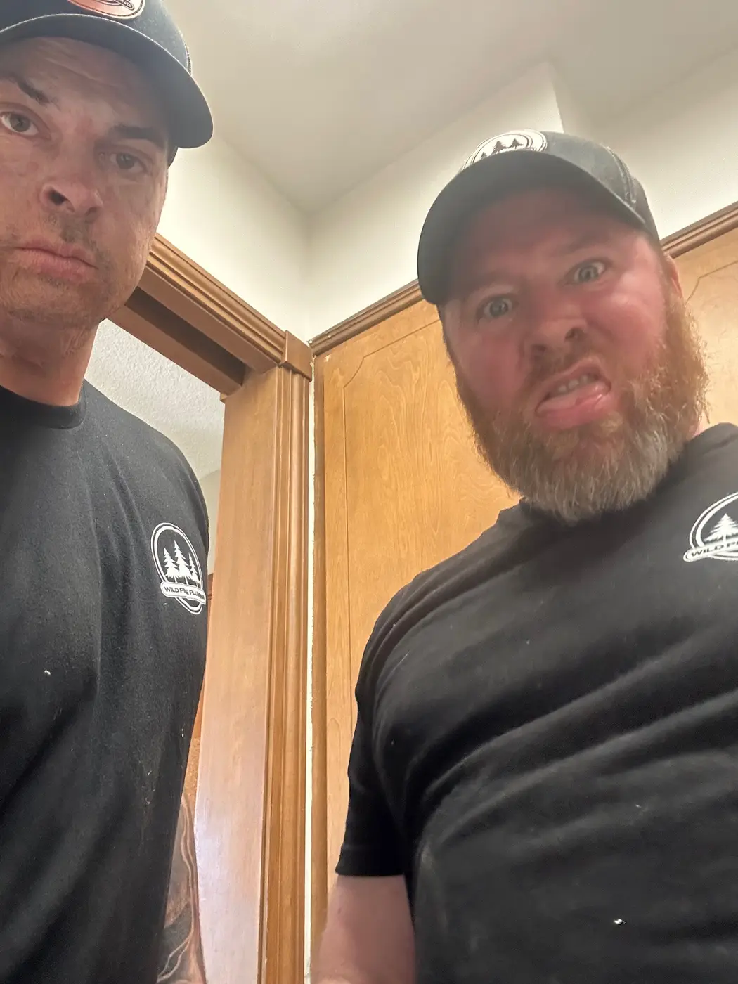 Wild Pine Plumbing two-man crew in branded shirts on a residential service call in St Helens, Oregon